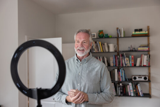 Senior male influencer recording a vlog at home