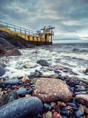 Fototapeta na wymiar Ocean waves and rocks by Blackrock diving tower, Salthill area, Galway city, Ireland. Popular city landmark and tourist viewpoint with stunning nature scenery. Vertical image.