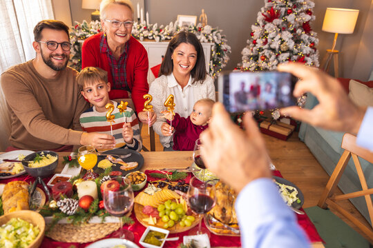 Senior man taking photos of his family while having Christmas dinner at home