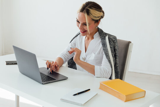 Image of young pleased happy cheerful cute beautiful business woman sit indoors in office using laptop computer
