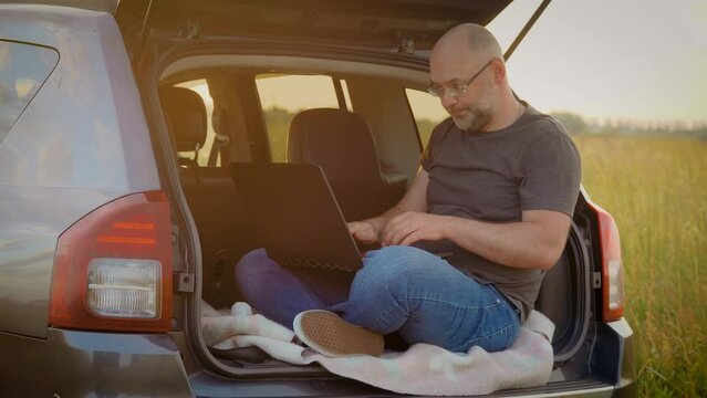 Tired Business Man Hard Work On Laptop Computer Deeply Breathing Sitting In Car Trunk While Traveling. Busy Worker Freelancer Entrepreneur Notebook Online Working Outdoors In SUV