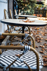 Street cafe tables covered with fallen leaves