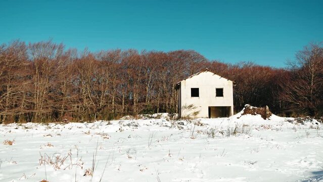 White house in the forest sorrounded by snow 