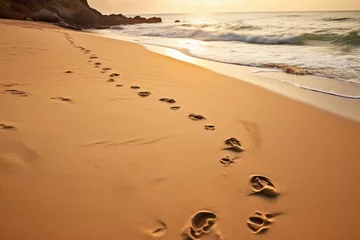 Fotobehang footprints in sand on the beach in the morning with beautiful light © Dina