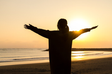Silhouette of woman stand at sunset in the beach with open arm