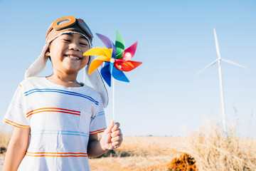 Child's playful involvement near wind turbines with a pinwheel toy celebrates wind energy....