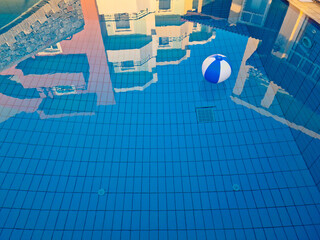 Pool im Hotelressort mit einem schwimmenden Ball und im Wasser spiegelnden Hotelanlage