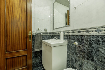 Small bathroom with a white wooden cabinet with a porcelain sink and a mirror built into the wall