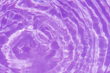 Purple water bubbles with ripples on the surface. Transparent pink colored clear calm water surface texture with splashes and bubbles. Water waves with shining pattern texture background.