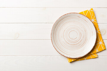 Top view on colored background empty round white plate on tablecloth for food. Empty dish on napkin...