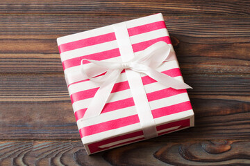 wrapped Christmas or other holiday handmade gift box in color paper with ribbon on colored background. Present box, decoration of gift on colored table, top view with copy space