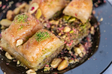 Traditional famous Turkish dessert baklava, pistachios and tea glass in black plate on marble background