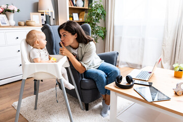 Mom and businesswoman working with laptop computer at home and playing with her baby. Female on...