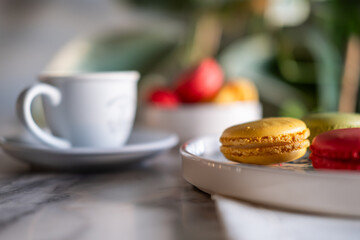 Colorful macarons and filter coffee on a blue plate