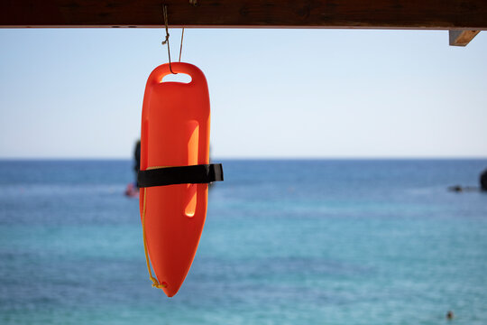 Life guard rescue can hanging against blue sea, red rescue buoy close up, hot summer day with calm sea