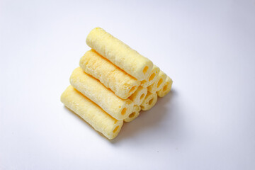 Crispy yellow corn sticks on a white background, close up