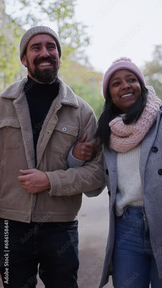 Wall mural Vertical video. Beautiful young couple interracial in love enjoying winter holiday season in the city streets, taking a walk, hugging and holding gift bags while celebrating Christmas outdoors