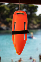 Close up life guard rescue can hanging against blue sea, red rescue buoy close up