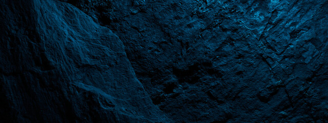Black stone texture in blue neon lighting, dark abstract background. Natural mineral rock close up...