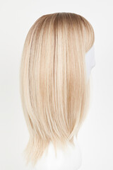 Natural looking blonde fair wig on white mannequin head. Middle length hair cut on the plastic wig...
