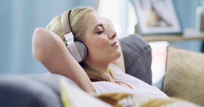 Woman, headphones and podcast on sofa for relax, music or streaming with internet in living room of home. Freedom, person and listening to audio, sound or track on couch of lounge for peace and break