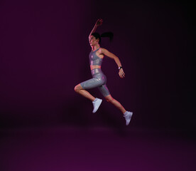 Fototapeta na wymiar Full length of slim woman jumping against magenta backdrop