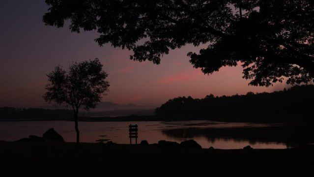 Time lapse light of sky and lake in morning amid nature and silhouette of trees stock video