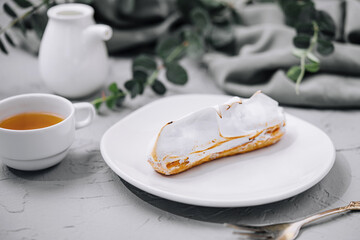 eclair with meringue and cup of tea