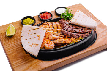 Beef chicken and shrimp fajitas on a iron cast sizzling plate