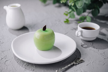 Green apple shaped mousse cake and cup of coffee