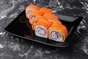 sushi rolls with salmon and crab on black plate