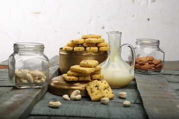 Whole grain cereal shortbread biscuits cookies stacked on black slate with cashew and hazel nuts. Selective focus on front of top cookie. High Resolution