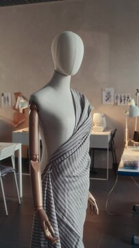 Vertical no people shot of white female mannequin with pinned striped fabrics in empty atelier