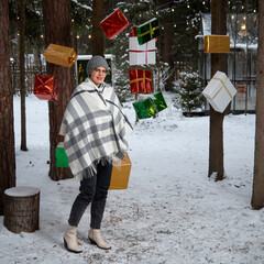 Woman standing among Christmas gifts hanging from tree branches