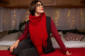 A woman in casual clothes lies on a bed in a room decorated for Christmas