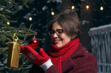 Woman next to a decorated Christmas tree set up on the street