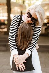 Fototapeta premium Happy young mother and little daughter are playing and fooling around outside.