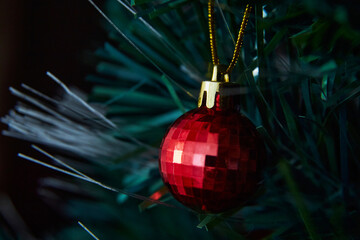 Red Christmas ball on the Christmas tree. Artificial pine branch. Preservation of the environment.