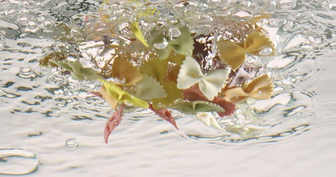 Farfalle tricolore pasta in boiling water. Shot on super slow motion camera 1000 fps.