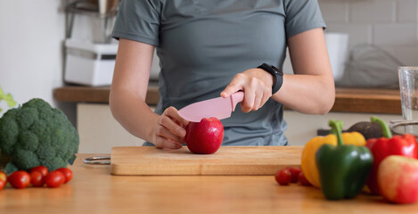 Healthy Asian woman takes care of her health by eating vegetable and fruit salad, adding vitamins in the kitchen.