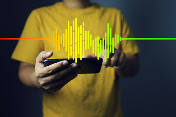 Music and sound wave concept with man in yellow t-shirt holding smartphone and playing music with...
