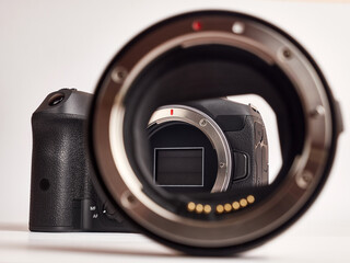 Digital mirrorless camera and compatible optical mount adapter on white background.