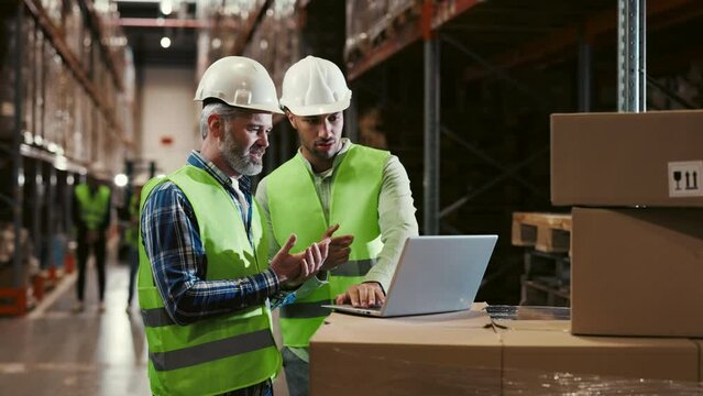 Diverse Employees Working at a Vast Logistics Center for an International Online Shopping Platform. Multi Ethnic Guy Using a Laptop with Colleague Colaborate with New Platforms