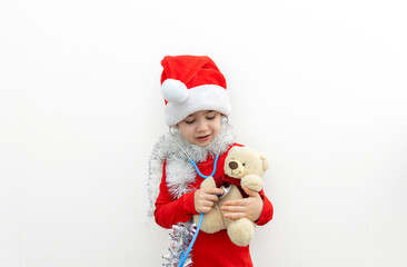 Fototapeta na wymiar cute boy with santa claus cap and stethoscope playing with teddy bear,listening patient breathing,heartbeat.preschooler kid in red clothes with garland and tangerine covering eyes.candy cane as heart