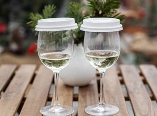 glass with sparkling wine and coffee cover on outdoor cafe table.girl taking photos,using smartphone,typing message.for christmas tree branches, happy new year.