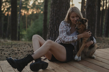 A young woman with her dog in a summer park. Happy girl walking in the woods with her mongrel dog. Concept of loving and helping dogs from a shelter.