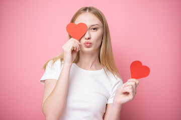 Portrait of attractive girl on pink background with red hearts for valentine's day. Concept of congratulations for holidays.
