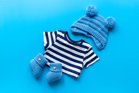 Set of baby boy dress - blue bodysuit with knitted hat and boots, top view. Kids clothing flat lay