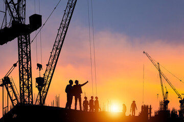 Silhouette of Engineer and worker checking project at construction site, building site with blurred...