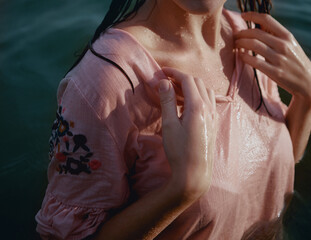 A lady in a wet pink dress in a body of water